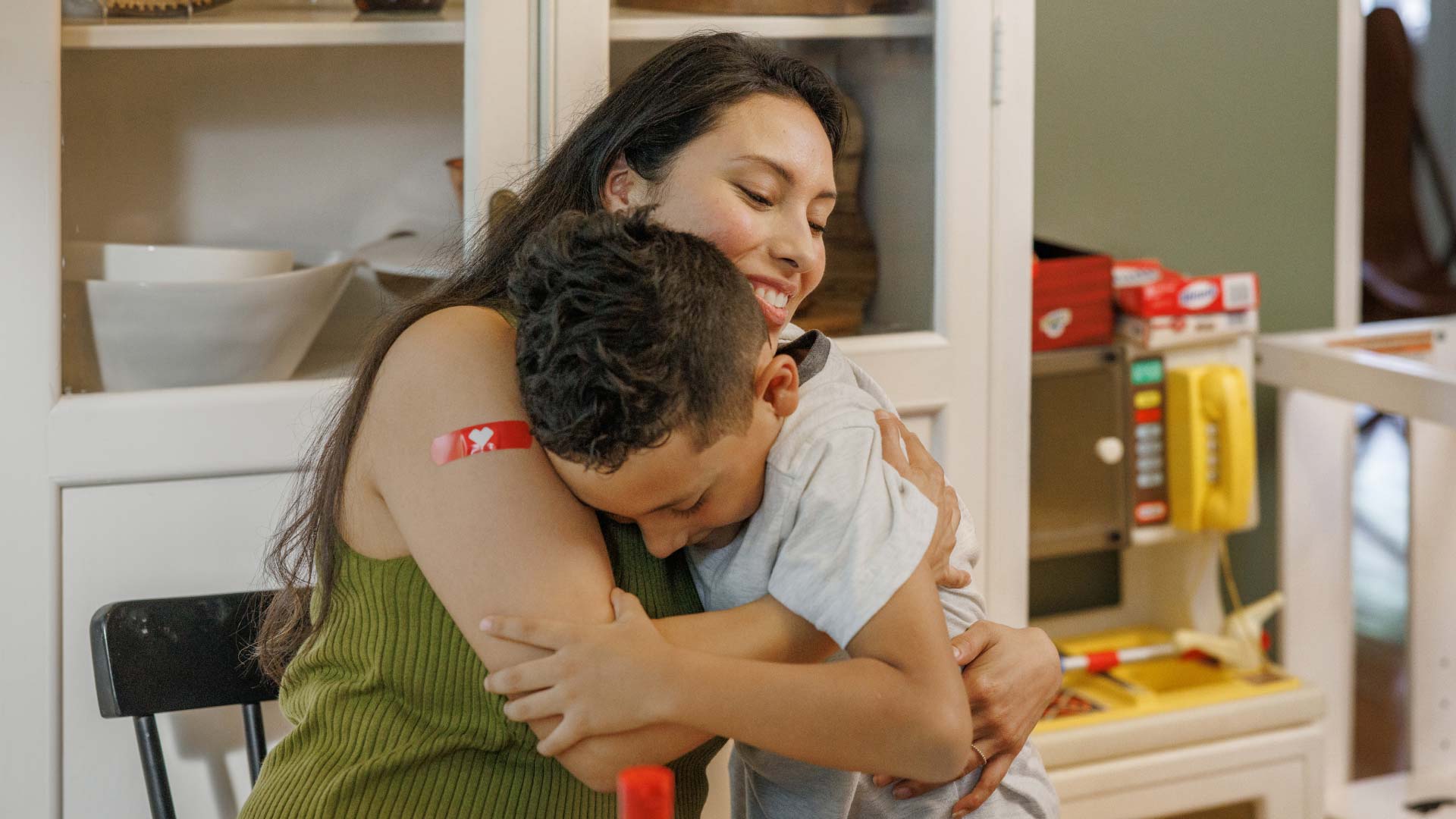 A parent smiles and hugs their child after they both get vaccinated.