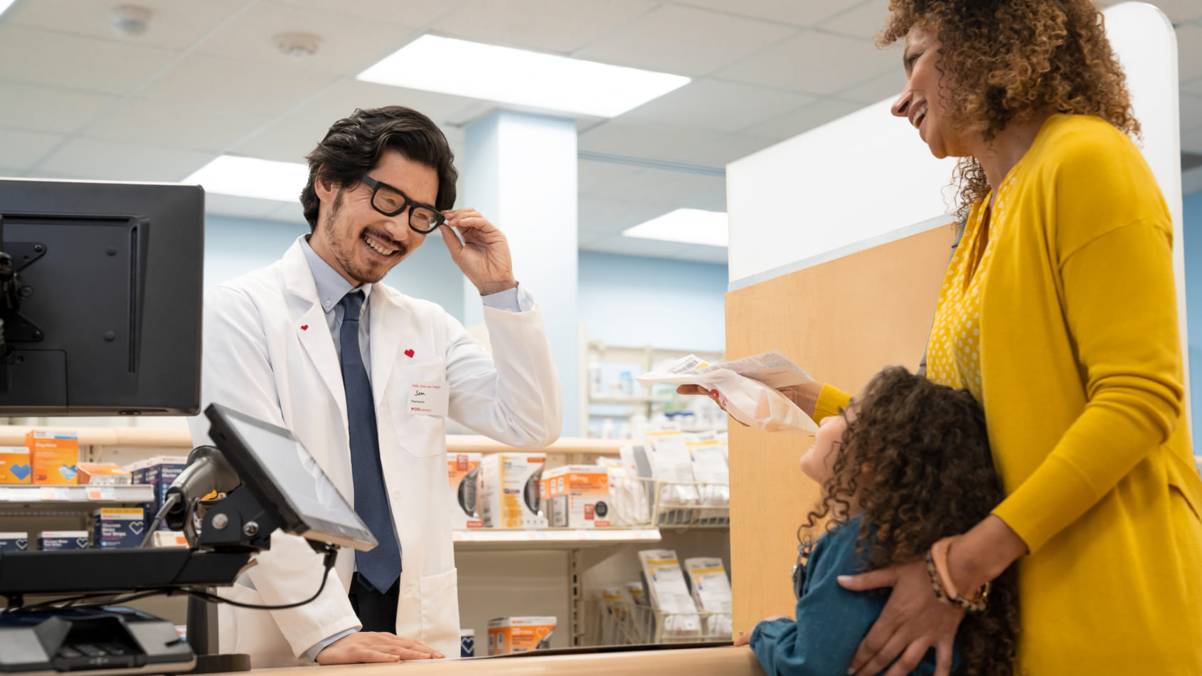 A CVS Pharmacist gives a parent a prescription for her daughter.